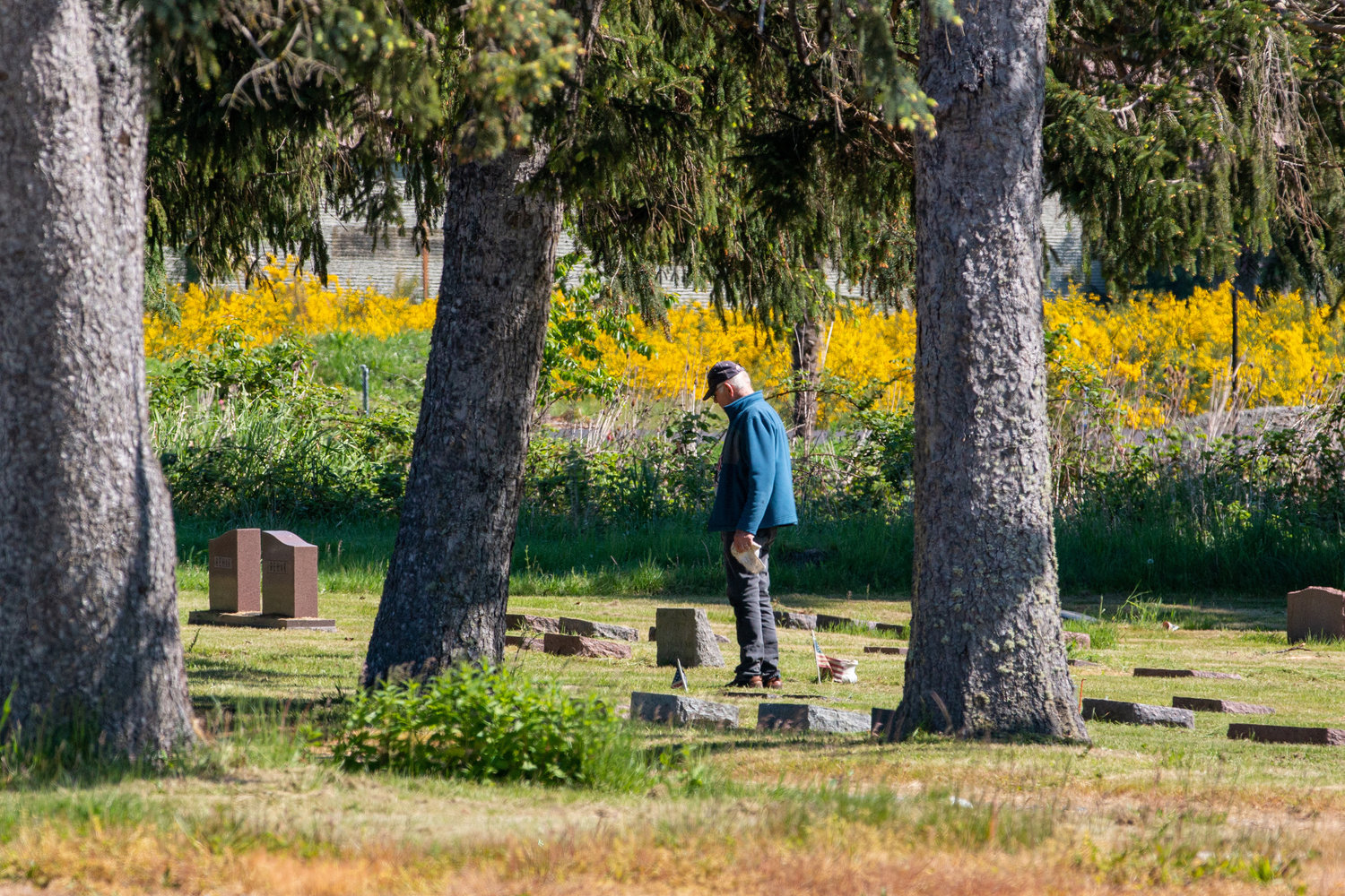 A man stands in front of a grave at the Greenwood Memorial Park in Centralia.